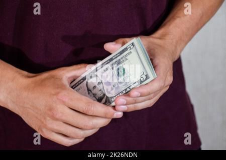 Der Mann hält einen Haufen Dollar in der Hand. US-Dollar Stockfoto