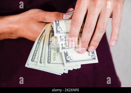 Der Mann hält einen Haufen Dollar in der Hand. US-Dollar Stockfoto