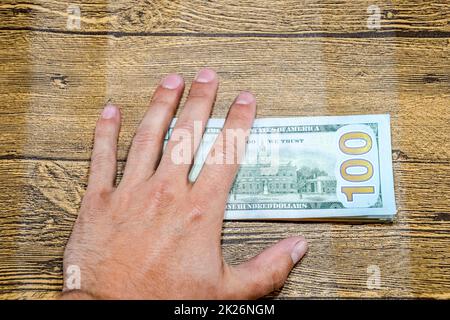 Der Mann am Tisch hält Rechnungen. Dollar in der Hand. Stockfoto