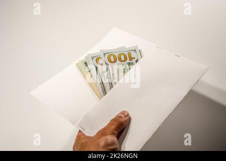 Dollars in einem Gegenwind auf weißem Hintergrund, eine Menge Geld in einem Umschlag. Stockfoto