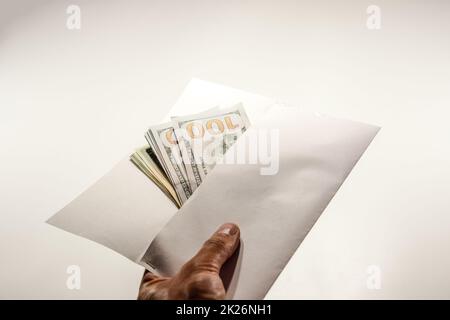 Dollars in einem Gegenwind auf weißem Hintergrund, eine Menge Geld in einem Umschlag. Stockfoto