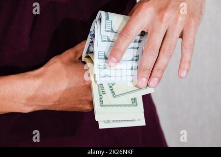 Der Mann hält einen Haufen Dollar in der Hand. US-Dollar Stockfoto