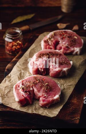 Raw Schweinelende Steaks mit verschiedenen Gewürzen Stockfoto