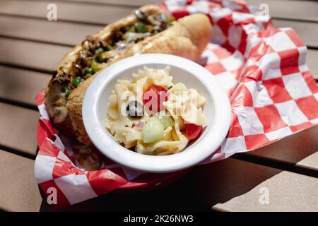 Ein Philly Cheesteak-Sandwich mit einer Beilage Nudelsalat in einem Retro-Korb Stockfoto