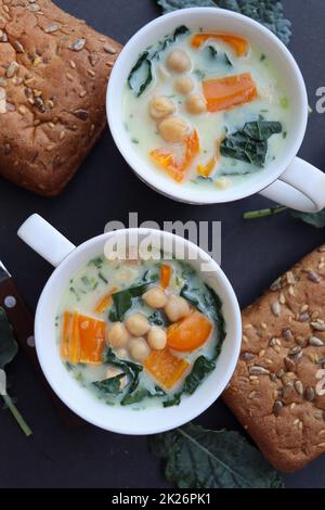 Weiße Suppe aus Kichererbsen, Grünkohl, Pfeffer und Kartoffeln in einer Schüssel auf dem dunklen Tisch. Draufsicht Stockfoto