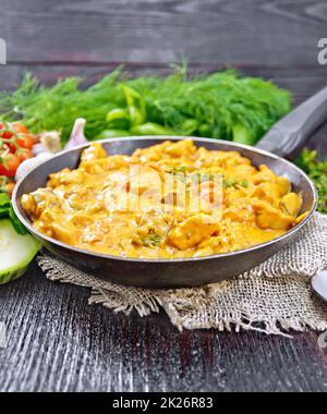 Gulasch mit Tomaten und Zucchini in der Pfanne auf dunklem Brett Stockfoto