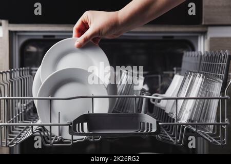 Offener Geschirrspüler mit sauberem Besteck, Gläsern, Geschirr in der Küche Stockfoto
