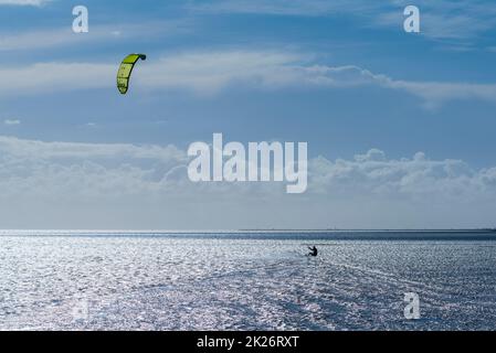 Kitesurfen an der Nordsee bei Lüttmoorsiel, Hallig Nordstrandischmoor am Horizont, Nrth Frisia, Norddeutschland Stockfoto