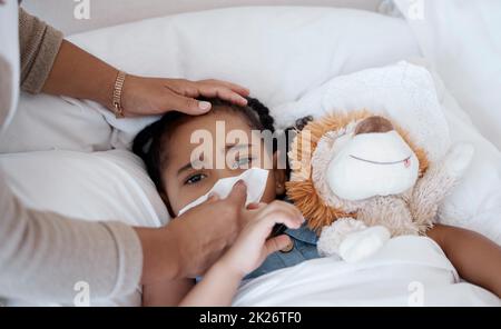 Krankes Kind, besorgte Mutter- und kovidhafte Symptome im Bett wegen Gesundheitsproblem oder Fieber beim Abwischen der Nase mit Gewebe. Frau kümmert sich um trauriges Mädchen mit Stockfoto