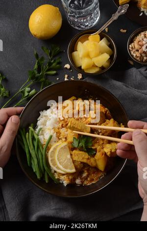 Ein Chicken Massaman Curry in schwarzer Schüssel auf dunklem Hintergrund. Massaman Curry ist das beste thailändische Gericht mit Hühnerfleisch, Kartoffeln, Zwiebeln und vielen Gewürzen, das von malaiischen und thailändischen muslimischen Kulturen beeinflusst wird. Stockfoto