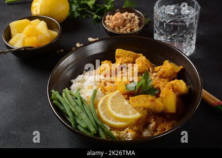 Ein Chicken Massaman Curry in schwarzer Schüssel auf dunklem Hintergrund. Massaman Curry ist das beste thailändische Gericht mit Hühnerfleisch, Kartoffeln, Zwiebeln und vielen Gewürzen, das von malaiischen und thailändischen muslimischen Kulturen beeinflusst wird. Stockfoto