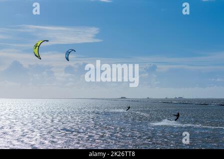 Kitesurfen an der Nordsee bei Lüttmoorsiel, Hallig Nordstrandischmoor am Horizont, Nrth Frisia, Norddeutschland Stockfoto