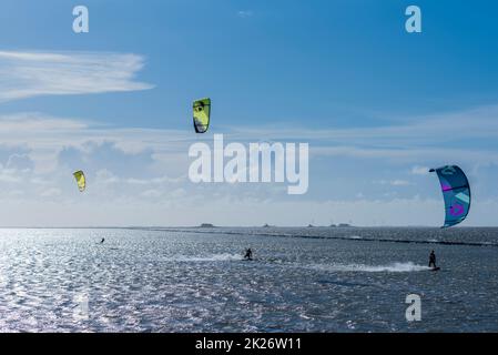 Kitesurfen an der Nordsee bei Lüttmoorsiel, Hallig Nordstrandischmoor am Horizont, Nrth Frisia, Norddeutschland Stockfoto