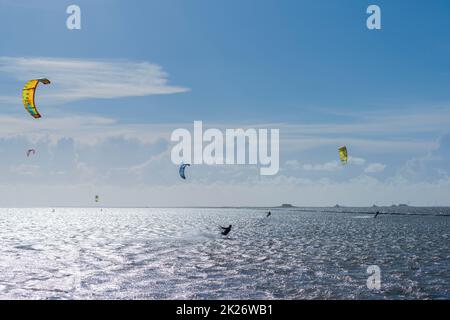 Kitesurfen an der Nordsee bei Lüttmoorsiel, Hallig Nordstrandischmoor am Horizont, Nrth Frisia, Norddeutschland Stockfoto