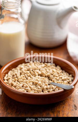 Frühstückscerealien. Hafer springt in die Schüssel auf den Holztisch. Stockfoto