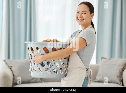 Glückliche asiatische Reinigungskraft Frau mit Wäscherei arbeitet für zu Hause, Haus oder Hotel Gastfreundschaft Reinigung Hilfe Service Agentur. Japanische Mädchen Magd oder Arbeiter lächeln Stockfoto