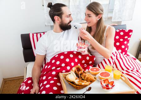 Junges Paar mit Frühstück im Bett Stockfoto