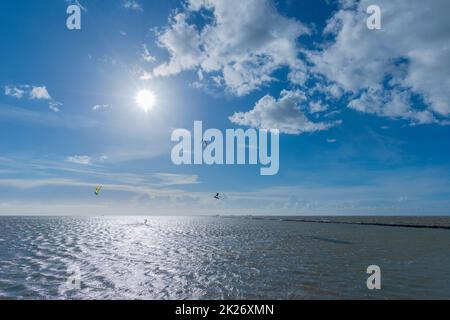 Kitesurfen an der Nordsee bei Lüttmoorsiel, Hallig Nordstrandischmoor am Horizont, Nrth Frisia, Norddeutschland Stockfoto