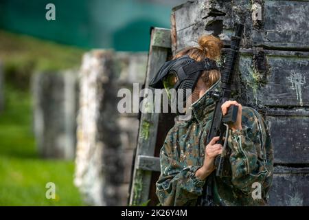 Junge Frau in Aktion beim Paintball spielen Stockfoto