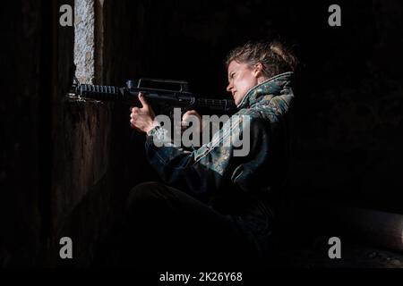 Junge Frau in Aktion beim Paintball spielen Stockfoto