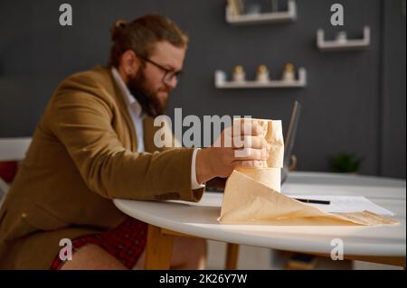 Gestresster Kerl Squeeze Papier Serviette arbeitet online Stockfoto