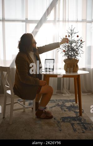 Freiberuflicher Geschäftsmann schmücken Tannenbaum mit Kugeln Stockfoto