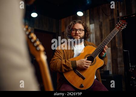 Musiklehrer, der die Eigenschaften des Gitarrenspiels erklärt Stockfoto