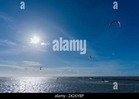 Kitesurfen an der Nordsee bei Lüttmoorsiel, Hallig Nordstrandischmoor am Horizont, Nrth Frisia, Norddeutschland Stockfoto