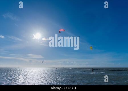 Kitesurfen an der Nordsee bei Lüttmoorsiel, Hallig Nordstrandischmoor am Horizont, Nrth Frisia, Norddeutschland Stockfoto