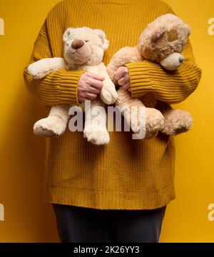 Frau in orange gestrickt Pullover Umarmungen niedlichen braunen Teddybär Stockfoto