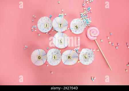 Es ist eine Grußkarte mit Girl Text auf Holzhintergrund mit pinkfarbenen Federn für Babys oder Neugeborene, Ansage-Grußkarte für Mädchen, Draufsicht in bunten Pastelltönen Stockfoto