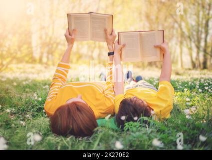 Mutter und ihr Sohn liegen auf dem schönen Frühlingsfeld im sonnigen Park. Stockfoto