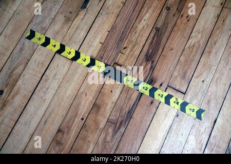 Der schwarze und gelbe Messpfeil klebt auf dem Holzboden Stockfoto