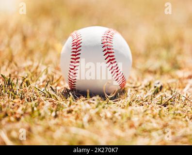 Baseballfeld, Sport- und Sportplatz auf Gras in der Natur auf einem Outdoor-Trainingsfeld. Weißer Ball auf dem Boden für Training, Cardio-Training und Fitness Stockfoto