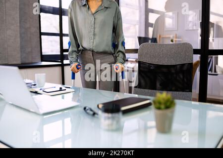 Behinderte Geschäftsfrau, Die Mit Krücken Läuft Stockfoto