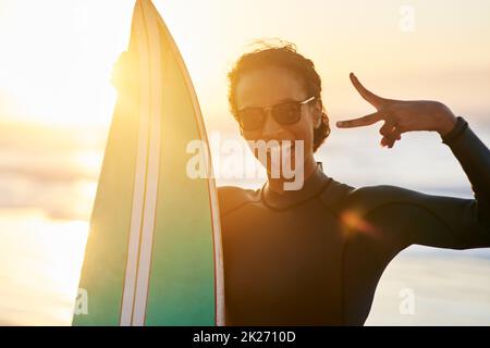 Kommen Sie und surfen Sie. Porträt einer schönen jungen Surferin, die mit ihrem Surfbrett am Strand posiert. Stockfoto
