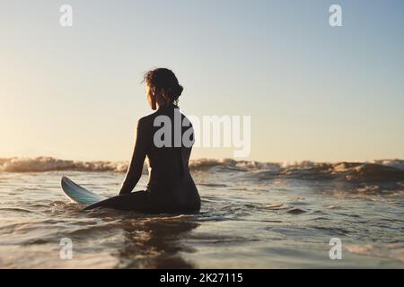 Sie ist so ruhig wie der Ozean. Rückansicht einer jungen Frau, die im Meer surft. Stockfoto