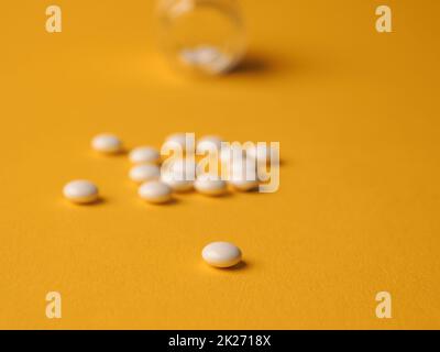 Weiße Pillen auf gelbem Hintergrund Stockfoto