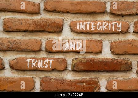Symbol für Vertrauen und Integrität. Konzeptwörter Vertrauen und Integrität auf roten Ziegeln auf einem schönen Backsteinwand-Hintergrund. Geschäft und Vertrauen und Integrität kontra Stockfoto