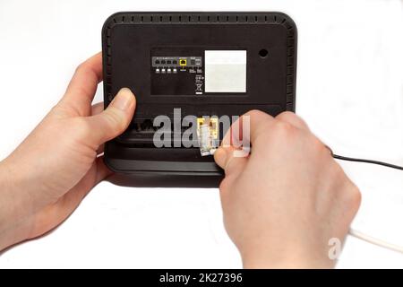 Hände halten den neuen WLAN-Router auf weißem Hintergrund. Neuer schwarzer Router wird ausgepackt. Stockfoto