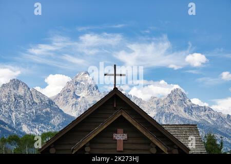 Blick auf das Kreuz auf der Spitze der Kapelle der Verklärung vor dem Grand Teton-Gebirge Stockfoto