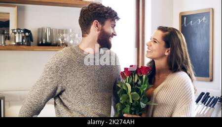 Schöne Rosen für meine schöne Frau. Aufnahme eines jungen Mannes, der seine Frau zu Hause mit einem Strauß Rosen überraschte. Stockfoto