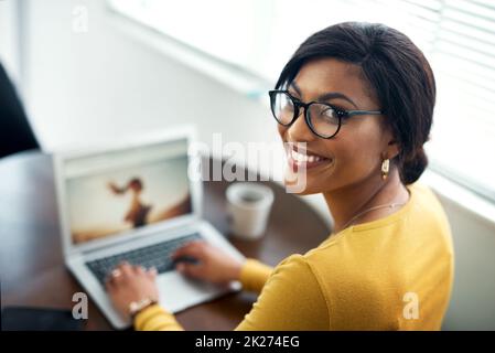 Die Arbeit erledigen. Eine kurze Aufnahme einer attraktiven jungen Frau, die allein in ihrem Haus sitzt und ihren Laptop benutzt. Stockfoto