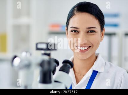 Ich bin ein Wissenschaftler, fragen Sie mich etwas. Porträt eines jungen Wissenschaftlers, der in einem Labor ein Mikroskop benutzt. Stockfoto