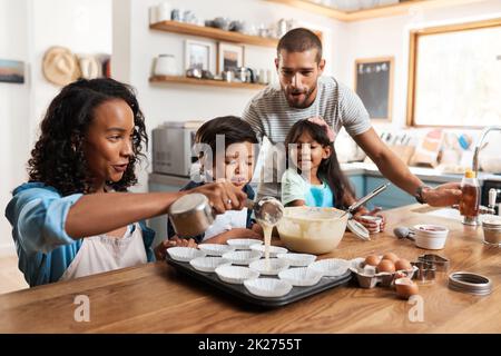 Hier beginnt die Magie. Eine kleine Aufnahme eines jungen Paares, das mit seinen beiden Kindern zu Hause backt. Stockfoto