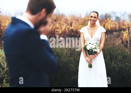 Ihre Schönheit bringt ihn zu Tränen. Aufnahme eines weinenden Bräutigams, während er seine schöne Braut an ihrem Hochzeitstag ansah. Stockfoto