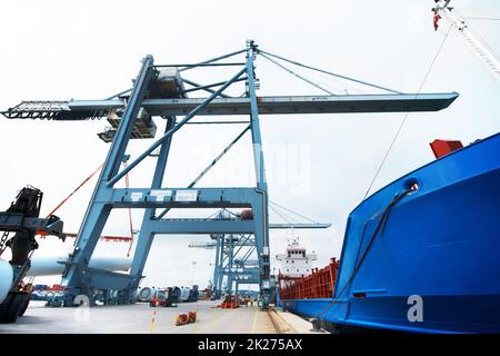 Der Hafen schläft nie. Ein massives Frachtschiff, das am Hafen festgemacht wurde, wurde mit Containern beladen. Stockfoto