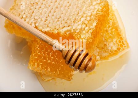 Frisch geschnittener Kammhonig und Holzstiel auf Weiß Stockfoto