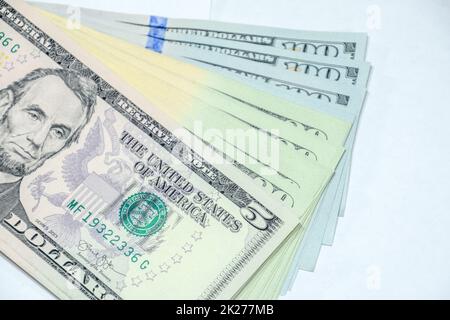 Die Zisterne der Banknoten liegt auf einem weißen Tisch. Eine Menge Dollar, ein Haufen Dollar. Stockfoto