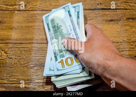 Der Mann am Tisch hält Rechnungen. Dollar in der Hand. Stockfoto